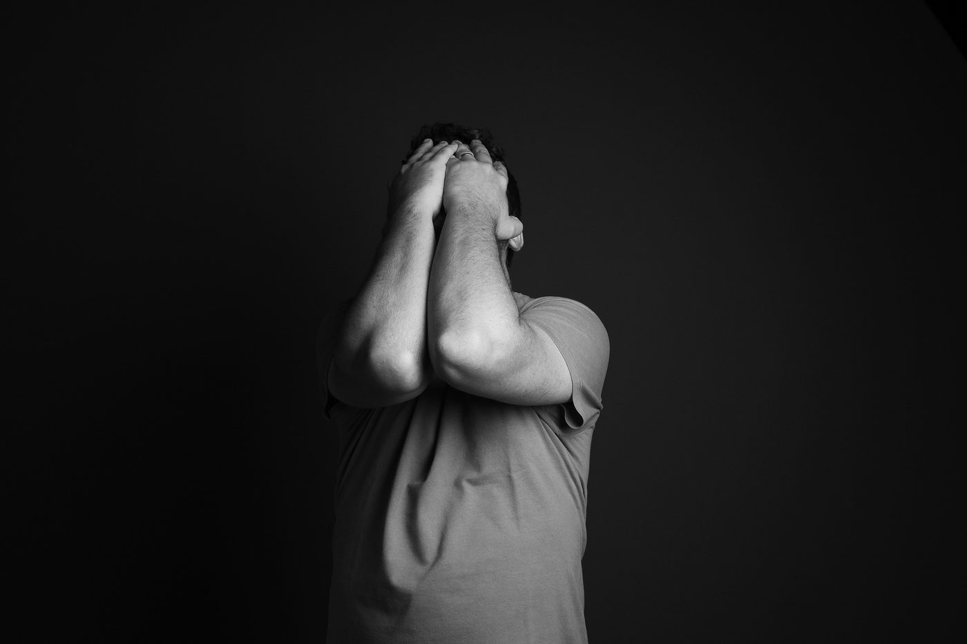 A black and white photo of a person sitting with their head in their hands, reflecting how heavy anxiety and depression can feel.