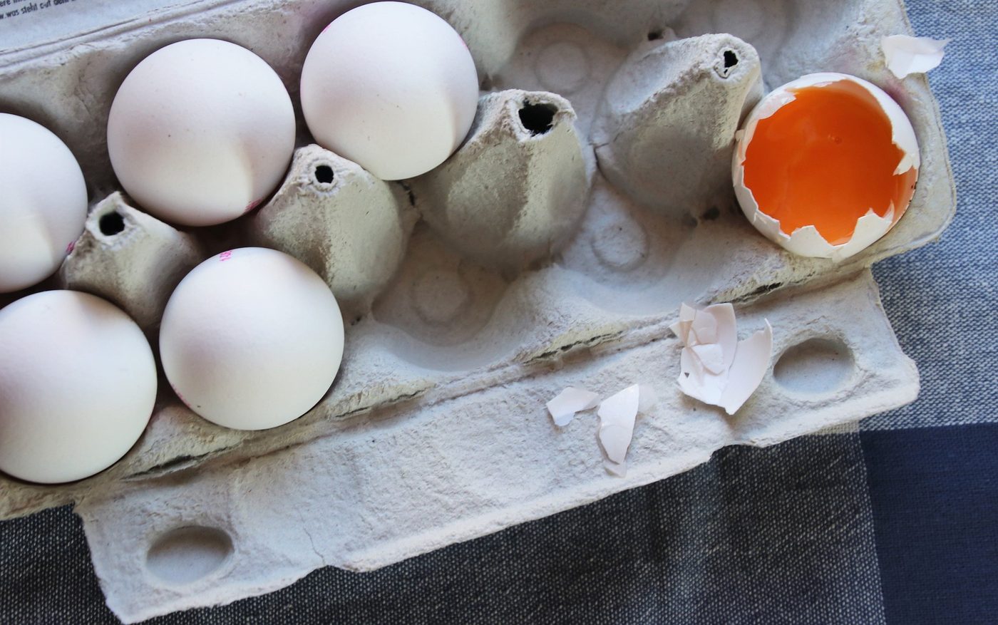 A carton of eggs with one cracked open, illustrating the dietary fat and cholesterol questions patients ask most often.