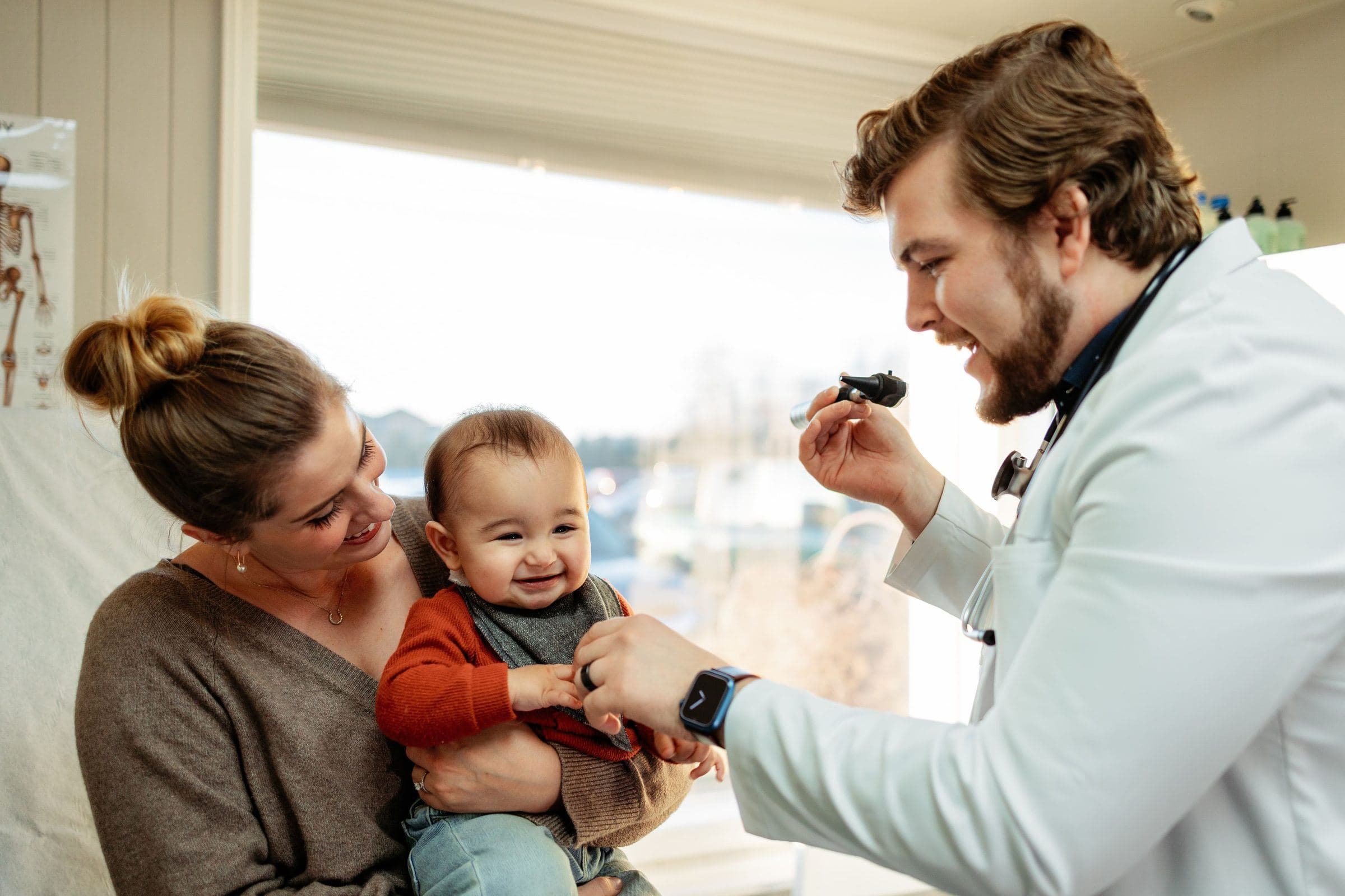 A Guardian Primary Care provider examining an infant while the child's mother holds them
