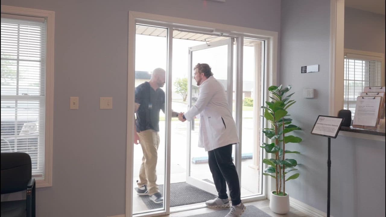 A Guardian Primary Care provider greeting a patient at the clinic entrance